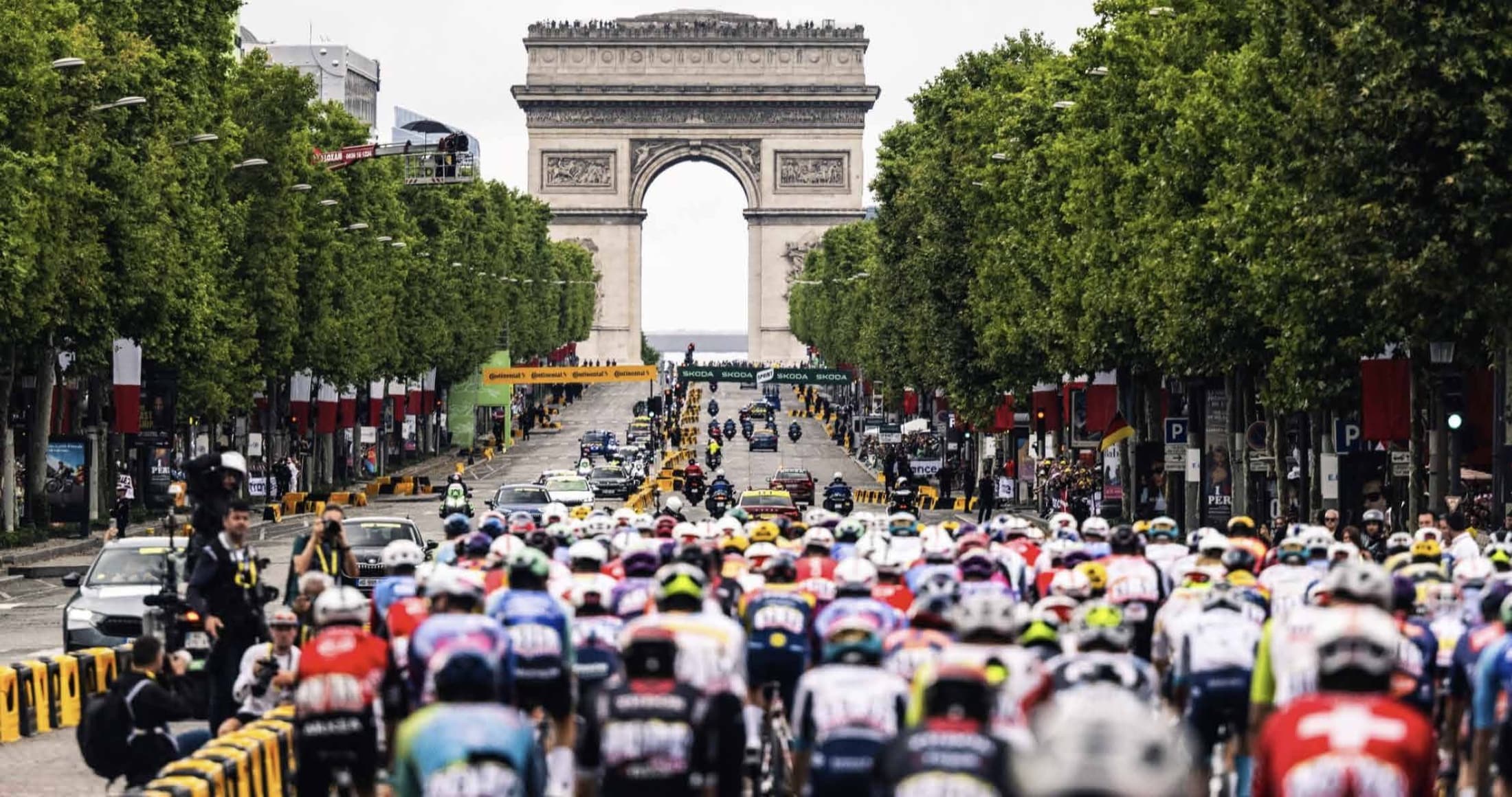 Tour de France peloton on the Champs-Élysées with the Arc de Triomphe