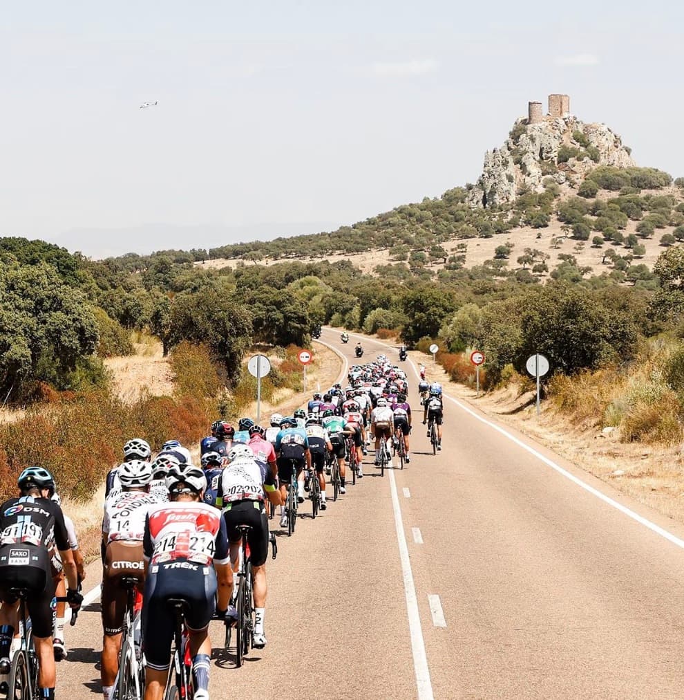 La Vuelta peloton on a Spanish road beneath a hilltop castle